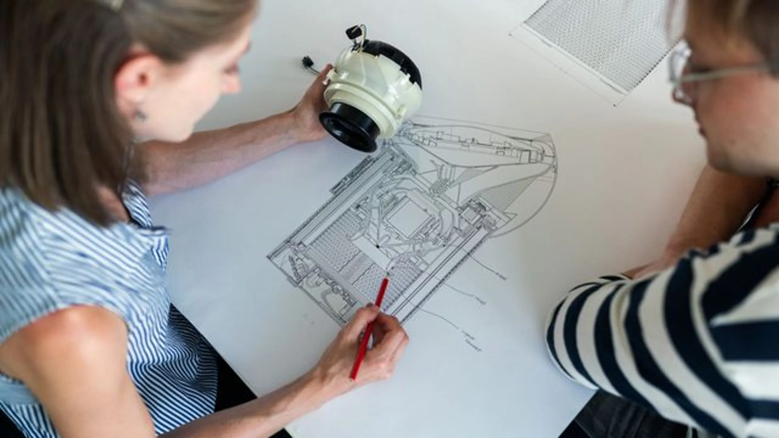 Engineering team reviewing a technical drawing at a work table.