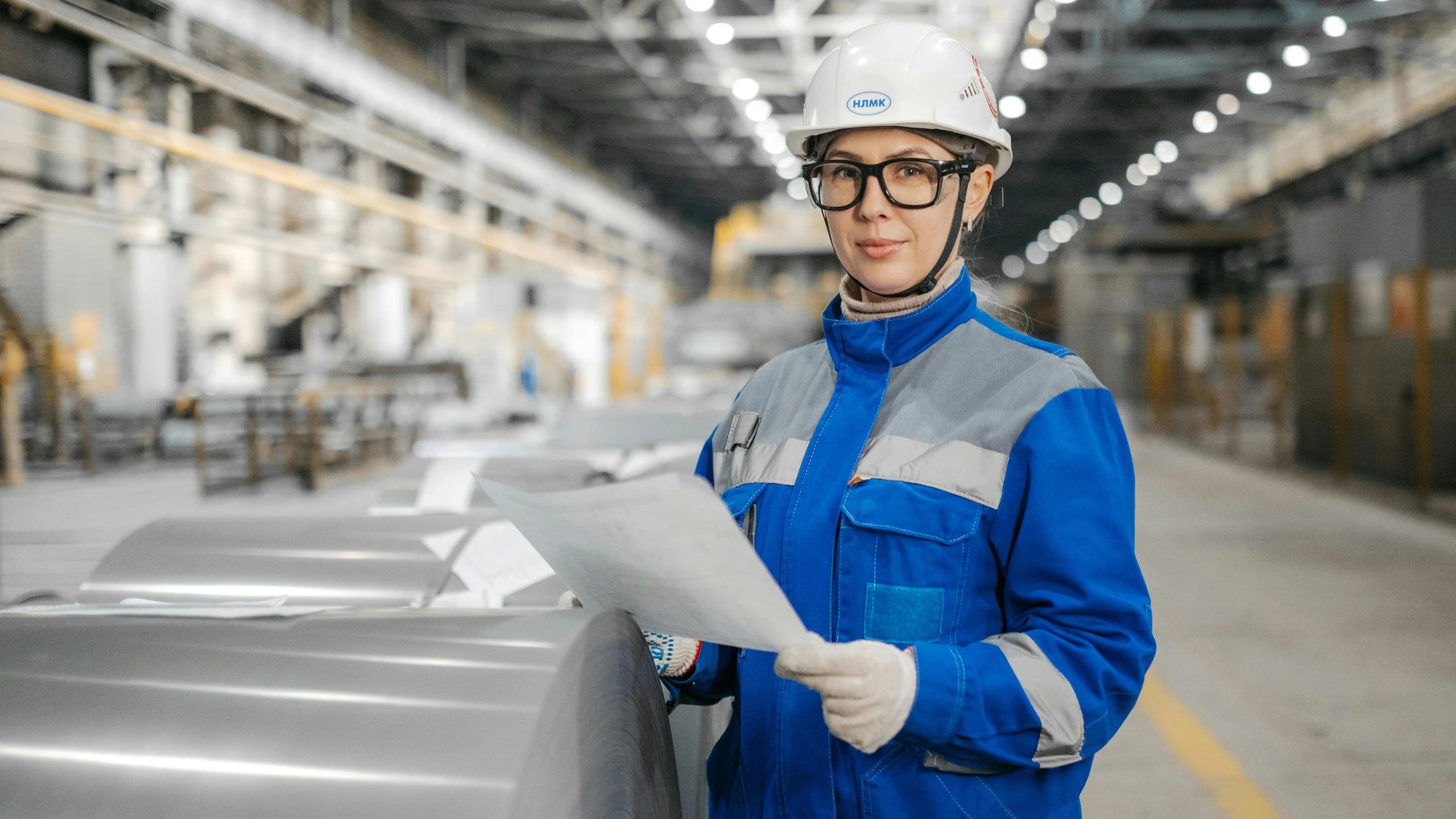 Industrial quality engineer holding documents on a factory floor.