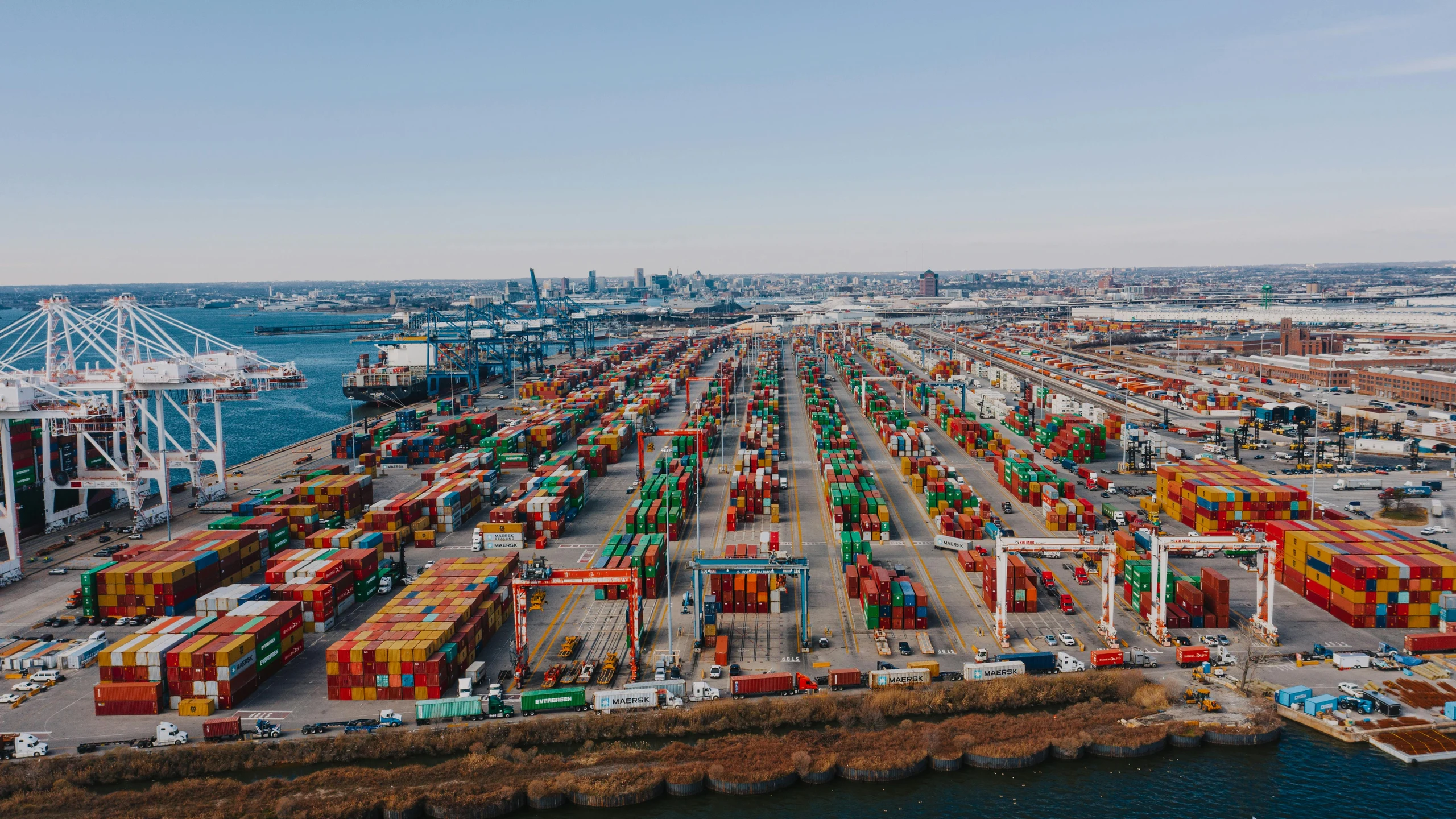Container port with stacked cargo containers and cranes.