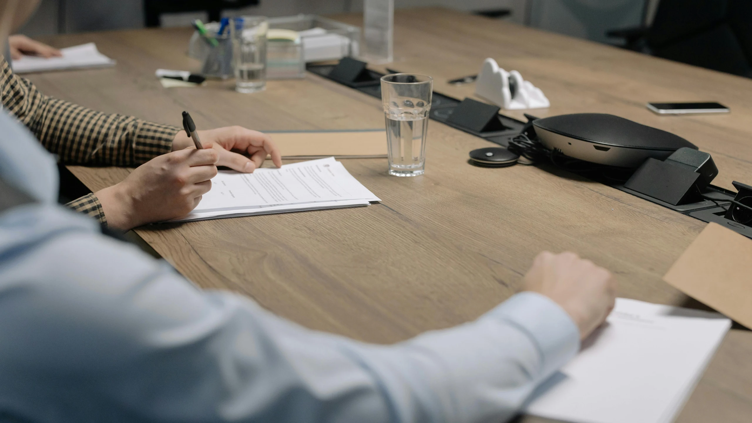 People reviewing and signing service documents at a meeting table.