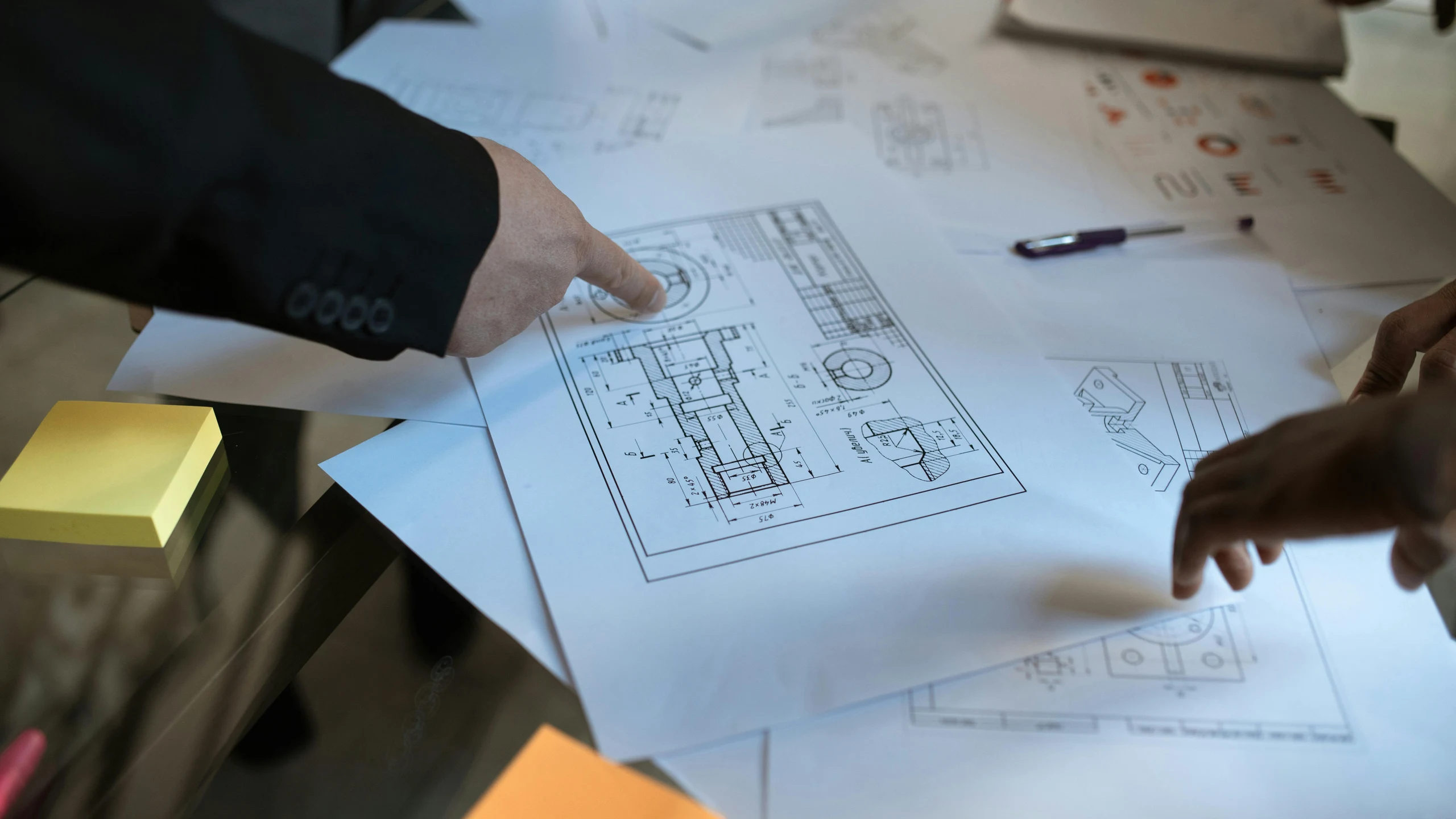 Hands reviewing a technical drawing during project planning.