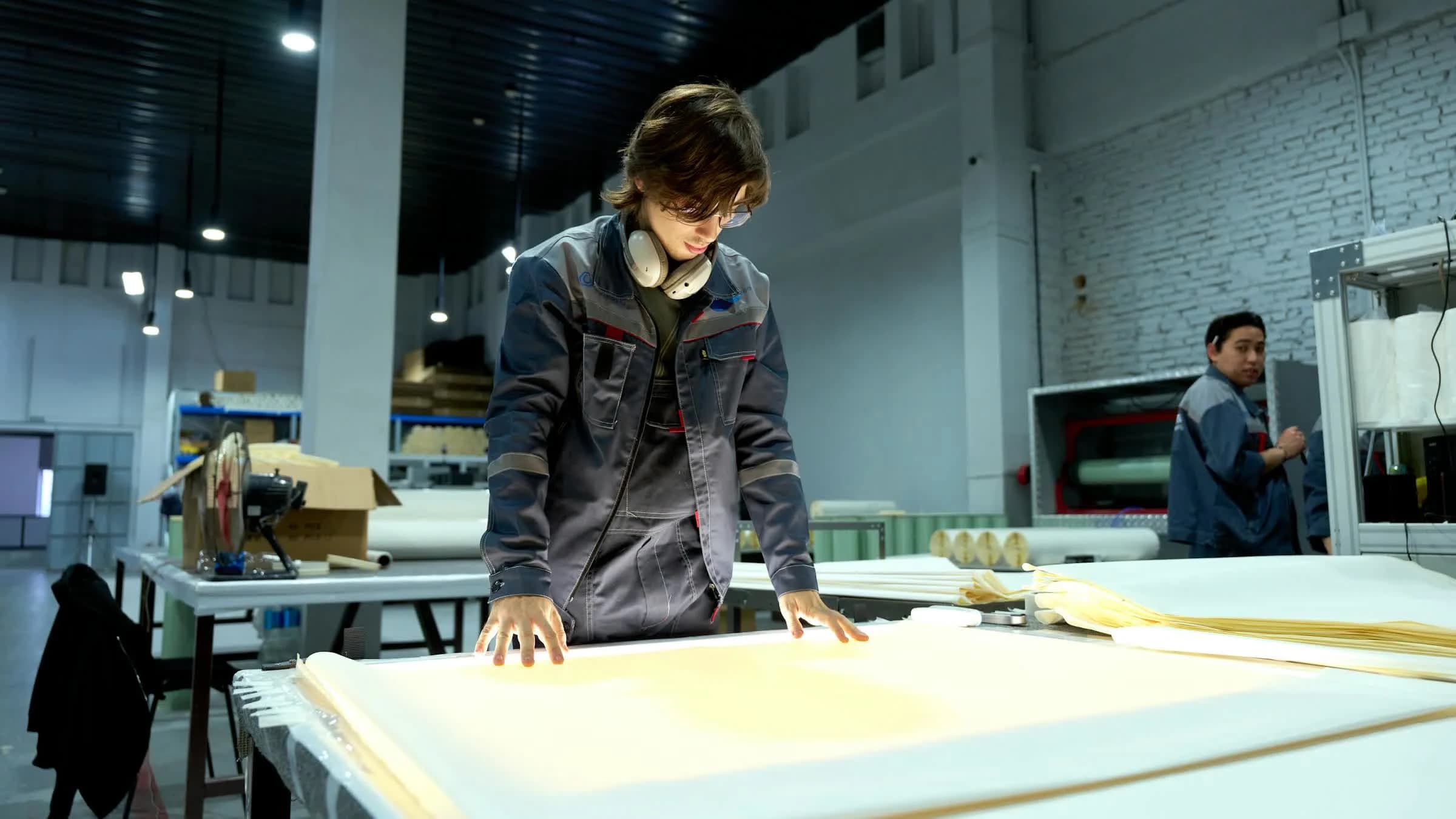 Factory worker inspecting production material on a light table.