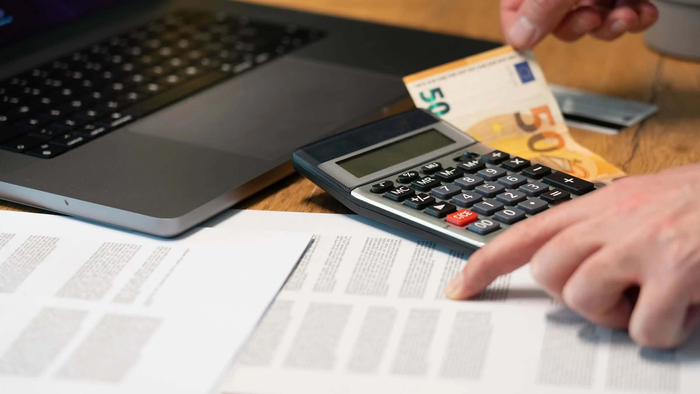 Calculator, euro note and reference documents used for checking import duty assumptions.